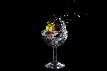 Mangosteen Dropped Into a Glass with a Big Splash , isolated on black