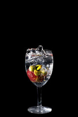 Mangosteen Dropped Into a Glass with a Big Splash , isolated on black