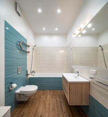 Modern interior of luxury bathroom. WC toilet. White bath and sink. Blue and beige tile.