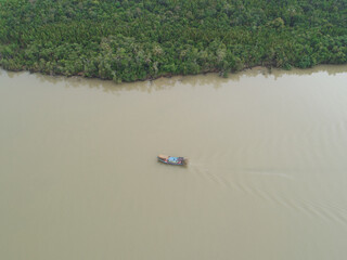 Aerial view of fishing boat sailing by the river bank