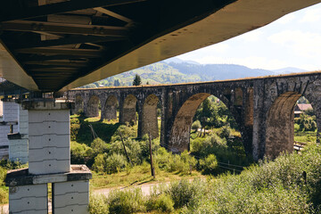 Panorama view of ancient bridge. Viaduct with old railway tracks near green hill of mountain forest. Locat travel concept