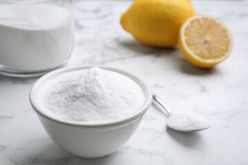 Fototapeta na wymiar Baking soda and cut lemons on white marble table