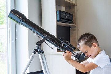 A boy looking through a telescope indoors