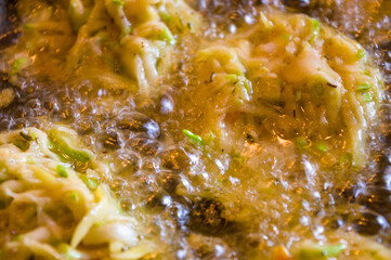Fried vegetable fritters with zucchini, carrots, herbs, eggs, and cheese in boiling oil.