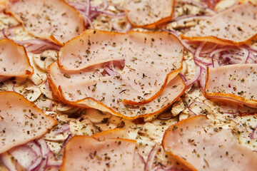 Delicious Italian Pizza with ham, onions and mozzarella cheese on dark background