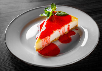 Strawberry cheesecake served on white plate on black wooden table background