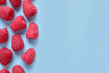 Fresh sweet ripe raspberries on light blue background, flat lay. Space for text