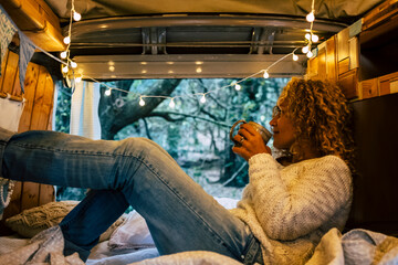Relaxed adult woman inside a vintage wooden van enjoy the natoure outdoor and the travel lifestyle...