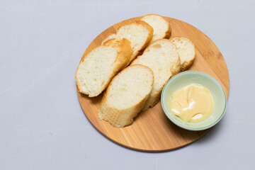 Butter on wooden holder surrounded by bread and milk on natural background