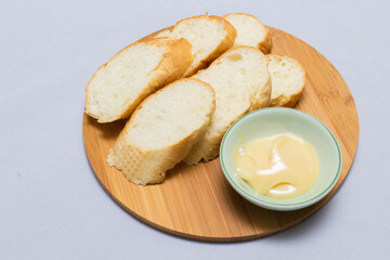 Butter on wooden holder surrounded by bread and milk on natural background