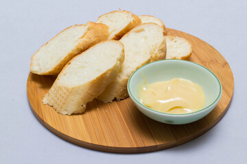 Butter on wooden holder surrounded by bread and milk on natural background