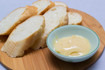 Butter on wooden holder surrounded by bread and milk on natural background