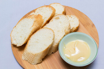Butter on wooden holder surrounded by bread and milk on natural background