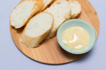 Butter on wooden holder surrounded by bread and milk on natural background