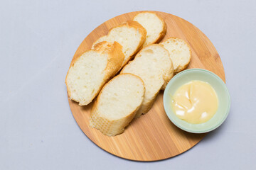 Butter on wooden holder surrounded by bread and milk on natural background
