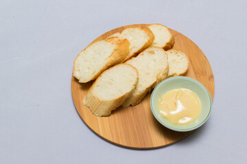 Butter on wooden holder surrounded by bread and milk on natural background