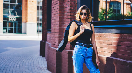 Young woman on street in sunny day with jacket in hand