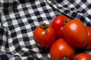 juicy red tomatoes in table cloth . caro background
