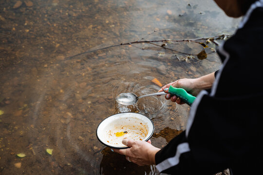 Wash Dishes With Your Hands In The River On A Hike. Wash Dishes With A Sponge, Camping Kitchen.