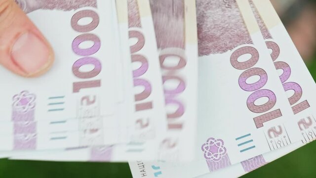 Cinematic shot: Men's hands consider Ukrainian money with a nominal value of one thousand hryvnias. Person counts banknotes. Man counts a large wad of money. Human hands with money