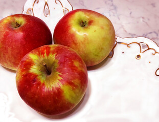 Three large red apples on a white dish on the table