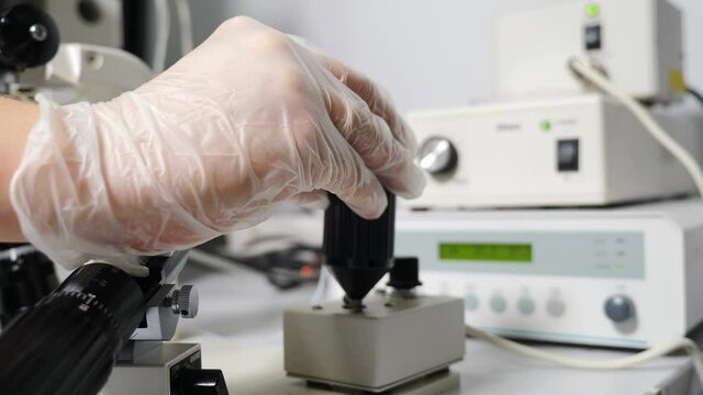 Artificial insemination in scientific laboratory under microscope. Fertility specialist performing icsi ivf procedure moving joystick to adjust micromanipulator needles. 4 k video