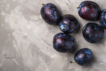 Fresh ripe plum fruits with water drops on stone concrete background, top view copy space