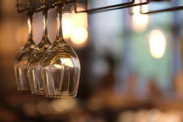 close up row of drinking glasses hanging upside down in bar. Bokeh background