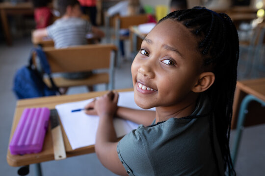 Portrait of smiling girl sitting at desk in school
