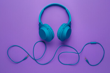 Blue headphone on purple background. Music concept.