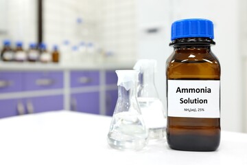 Selective focus of ammonia solution or ammonium hydroxide in glass amber bottle inside a chemistry laboratory with copy space.