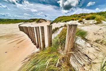 Dunes hollandaises, cultivées avec Beach Grass, prises avec un grand angle par une journée ensoleillée et nuageuse.