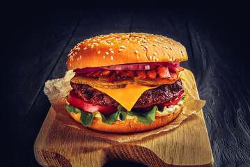 Beef burger with melted cheese and bacon on wooden background