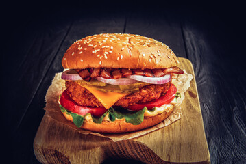 Beef burger with melted cheese and bacon on wooden background