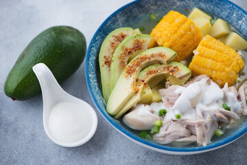 Closeup of colombian ajiaco or potato, chicken and corn soup topped with avocado and sour cream, selective focus, studio shot