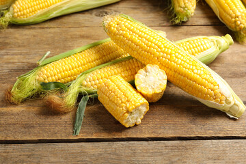Tasty sweet corn cobs on wooden table
