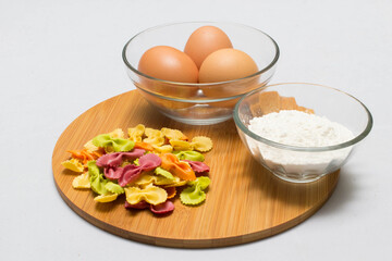 Raw homemade pasta and ingredients for pasta on wooden background