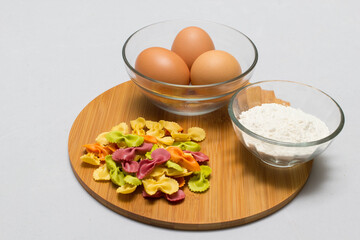 Raw homemade pasta and ingredients for pasta on wooden background