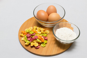 Raw homemade pasta and ingredients for pasta on wooden background