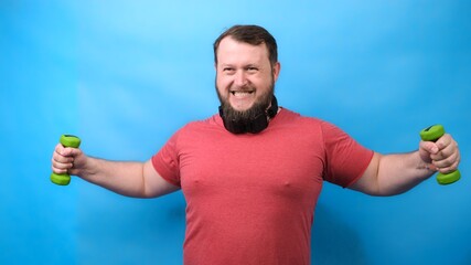 Thick bearded nice bodybuilder in pink T-shirt with very small dumbbells is very tense doing exercises