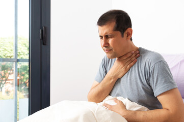 Shot of a handsome young man suffering touching painful neck, sore throat for flu, cold and...