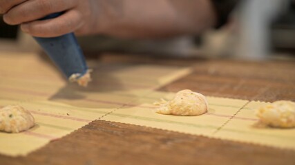 Stuffing tortellini on wooden table at the restaurant kitchen. Male hands squeezing filling from pastry bag to make tortellini, process of italian food making