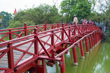 Fototapeta na wymiar The Huc Bridge or Sun shine bridge at Hoan Kiem Lake, It`s a red wooden arch bridge. 