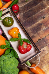 Small wooden box with color fresh ripe farm tomatoes and vegetables on old rustic table with copy space. Vertical orientation. Top view. Advertising healthy natural food. Vegetable harvest.