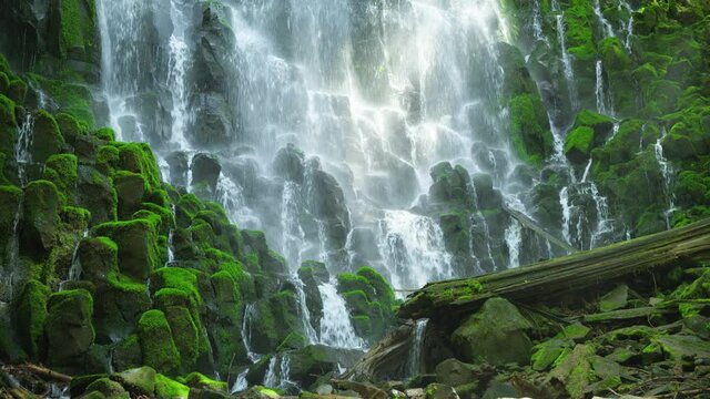 Waterfall cascades over mossy rocks in Oregon, low angle