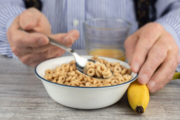 close up of an elderly man's hands holding a spoon full of breakfast cereal