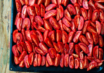  Tomatoes cut into wedges on a black pan. Tomato dishes. Tomato background.
