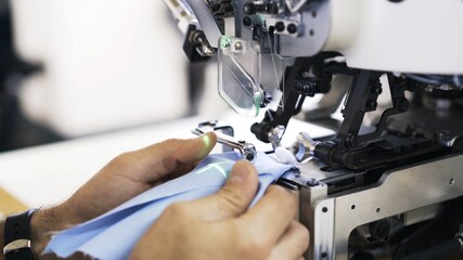 Sewing on machine and green laser, needle and hands with and blue cloth close up. Sewing process, female hands getting blue cloth to a modern white machine