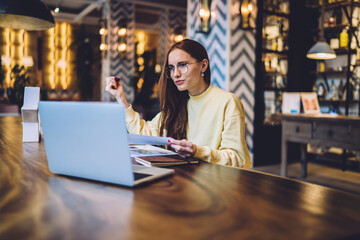 Fototapeta premium Woman in glasses sitting in cafe with laptop