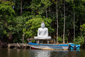 A large white Buddha statue on the Bentota Ganga river in the jungle on the island of Sri Lanka